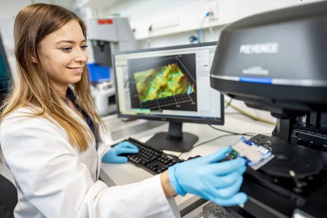 A scientist examines samples under the microscope